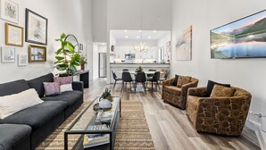 A modern living room with a sofa, armchairs, a coffee table, and a dining area with chairs and a table. - Luxury Ski-In Condo | 2023 Remodel | Walk to Peak 9 Lift and Mountain Views (Breckenridge)