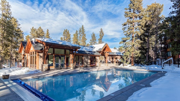 A resort with a pool, wooden cabins, and snow-covered ground. - Luxury Ski-In Condo | 2023 Remodel | Walk to Peak 9 Lift and Mountain Views (Breckenridge)