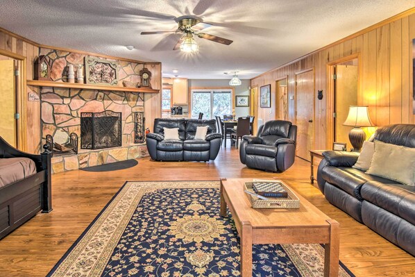 A spacious living room with a fireplace, leather sofas, a coffee table, and a large rug. - Secluded 'Lavinder Laurel Leaf Cottage' Near Creek (Lakemont)