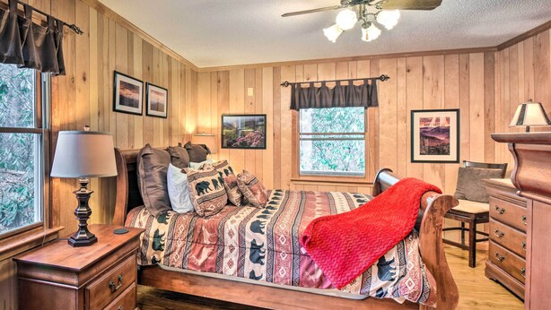 Une chambre aux murs lambrissés, avec un lit, une commode et un bureau doté d’une lampe.