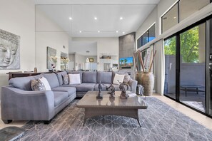 A modern living room with a sectional sofa, a coffee table, and a large window with a view.