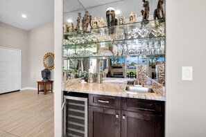 A kitchen with a glass-fronted cabinet displaying various glassware and a Buddha statue on a side table.