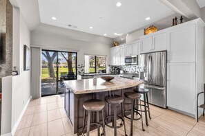 A modern kitchen with a large island, stainless steel appliances, and a view of a golf course.