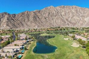 Una zona residencial con casas, un campo de golf y una montaña al fondo.