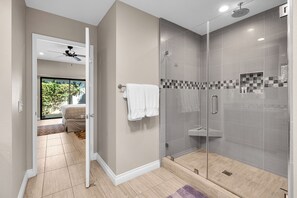 Ein modernes Badezimmer mit einer gläsernen Duschkabine, einem sichtbaren Handtuchhalter und einem Deckenventilator.