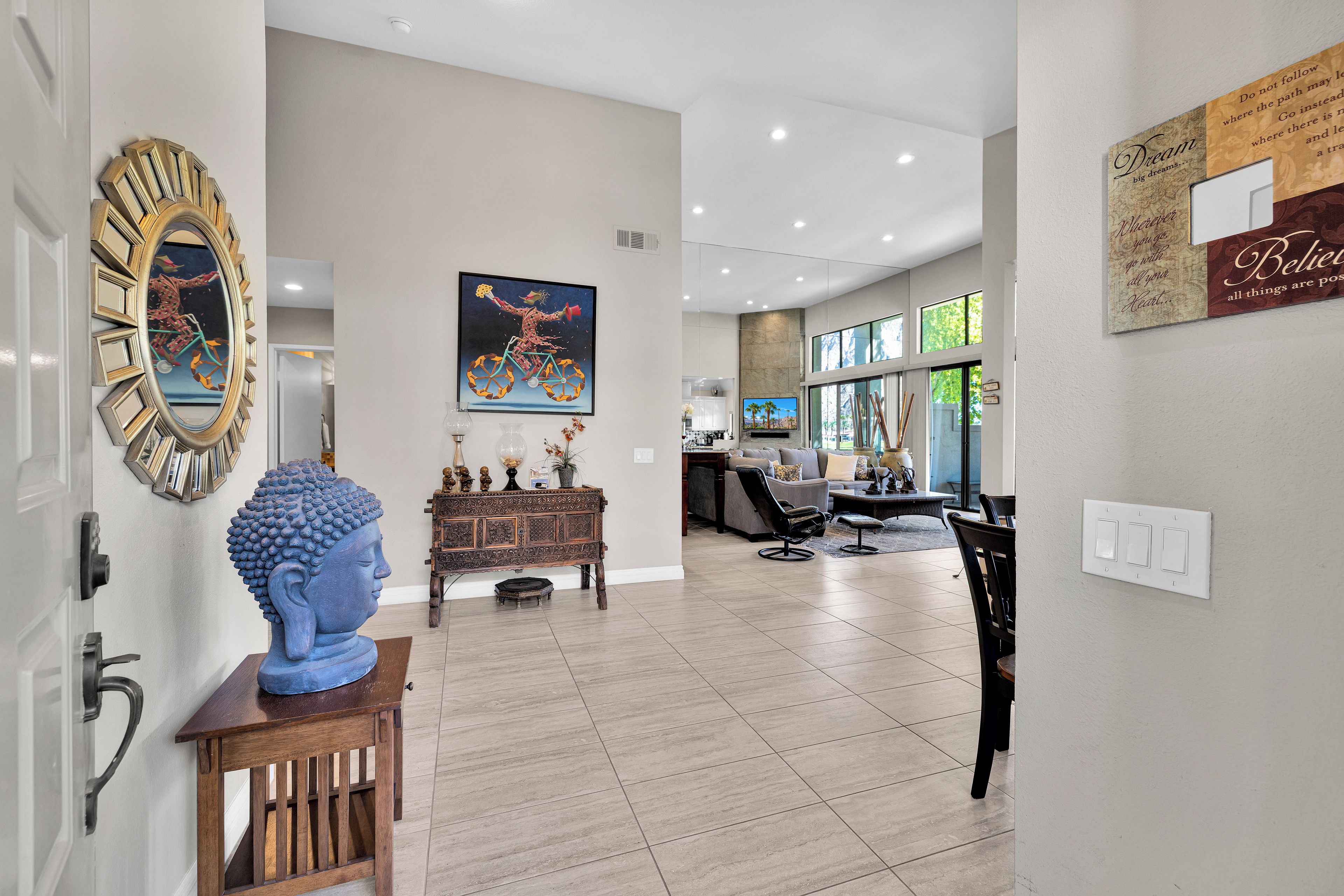 A modern interior with a Buddha statue, a colorful painting, and a dining area with a sofa and chairs.