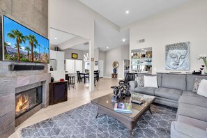 Un salón espacioso con chimenea, un televisor de pantalla plana grande y un sofá moderno.