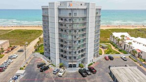 Un hotel de varios pisos con una entrada principal, estacionamiento y vistas a la playa.