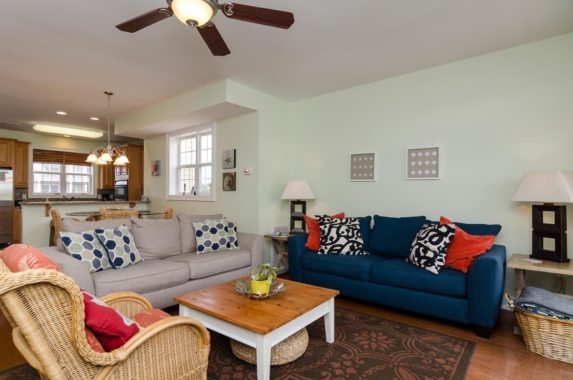 A living room with a sofa, two chairs, a coffee table, and a ceiling fan.