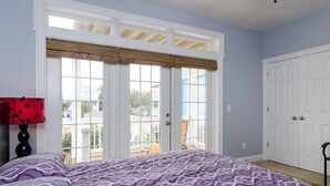 Un dormitorio con cama, ventana con vistas y puerta.