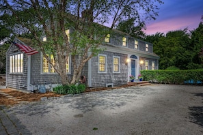 A two-story house with a front porch, a flag, and a well-maintained lawn.