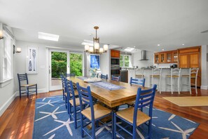A dining area with a wooden table, blue chairs, and a patterned rug.