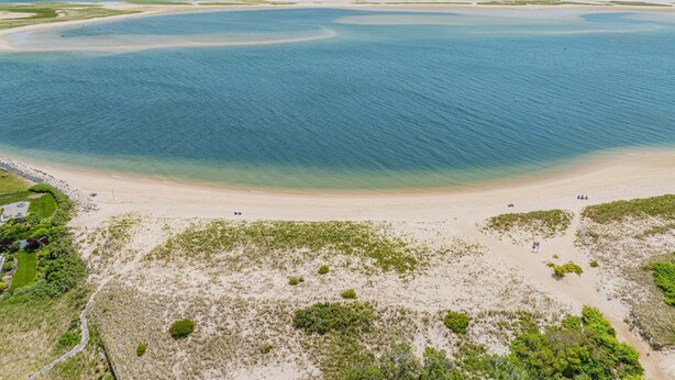 Eine Luftaufnahme einer Küstenlandschaft mit Strand, klarem Wasser und spärlicher Vegetation.