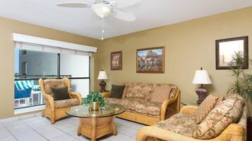 A living room with wicker furniture, a glass coffee table, and a ceiling fan.