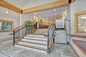 Staircase leads to an upper level, flanked by wooden beams and a black railing.
