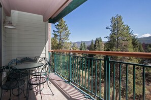 Enjoy breathtaking views of the surrounding mountains from this balcony with a table and four chairs.