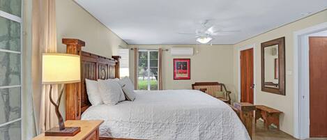 A bedroom with a wooden bed, a bedside table, a lamp, and a window with curtains.