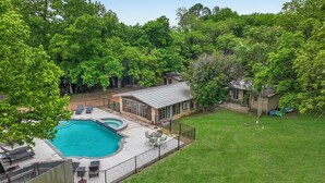 A backyard with a swimming pool, a covered patio, and a stone building.