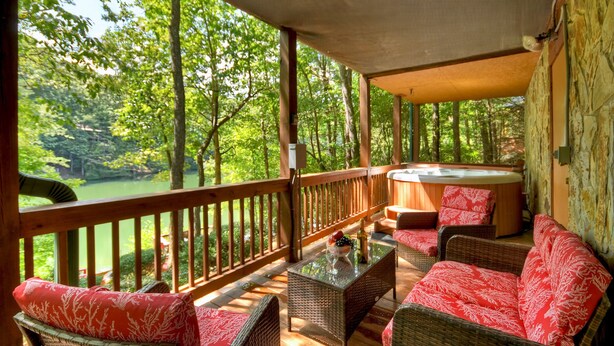 Un espacio exterior cubierto con mobiliario de mimbre, un jacuzzi y vistas a un área boscosa.