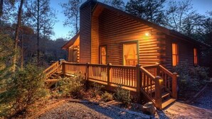 Una cabaña de troncos con terraza de madera y chimenea.