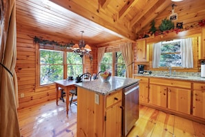 Cocina de cabaña de madera con una isla central, armarios de madera y ventanas amplias.