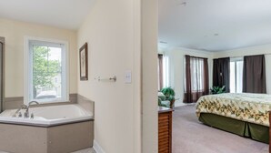 A bedroom with a large bed, a bathroom with a bathtub, and a window with blinds. - Beautiful and spacious townhouse located on the boardwalk with a pool! (OCEAN CITY)