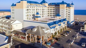 A large hotel with multiple buildings, a parking lot, and a beach in the background. - Beautiful and spacious townhouse located on the boardwalk with a pool! (OCEAN CITY)