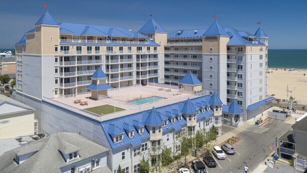 A large hotel with multiple floors, a swimming pool, and a beach view. - Beautiful and spacious townhouse located on the boardwalk with a pool! (OCEAN CITY)