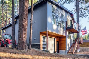 A modern two-story house with a garage, wooden deck, and a staircase leading to an upper level. - Family Home w/ Hot Tub, 2 Mi to El Dorado Beach! (South Lake Tahoe)