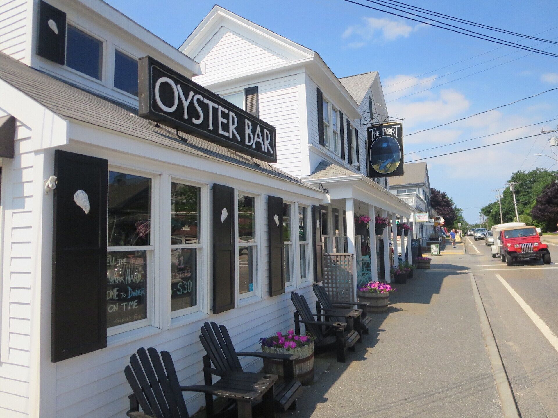 Un edificio blanco con un letrero que dice "OYSTER BAR" y un letrero más pequeño para "THE PORT".