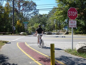 A person riding a bicycle on a paved path with a stop sign and a 'Walk Do Not Ride' sign. - Harwich Port Retreat—Walk to Beach & Rail Trail (Harwich Port)