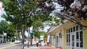 A yellow building with a sidewalk and trees.