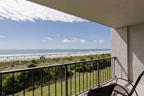 Ein Balkon mit Blick auf Strand und Meer.
