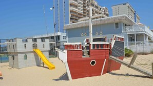 A beach-themed play area with a slide and a ship-shaped structure. - Comfortable, cozy 3-bedroom oceanfront condo with free WiFi, a breathtaking ocean view, an indoor and outdoor pool, and more located uptown and mere steps to the beach! (Ocean City)