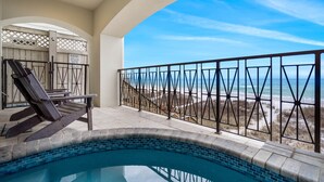 A pool area with a view of the beach, a lounge chair, and a sign indicating a private beach access.