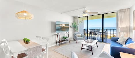 Relax in a spacious living room with a dining area, comfortable seating, and a large window offering ocean views.
