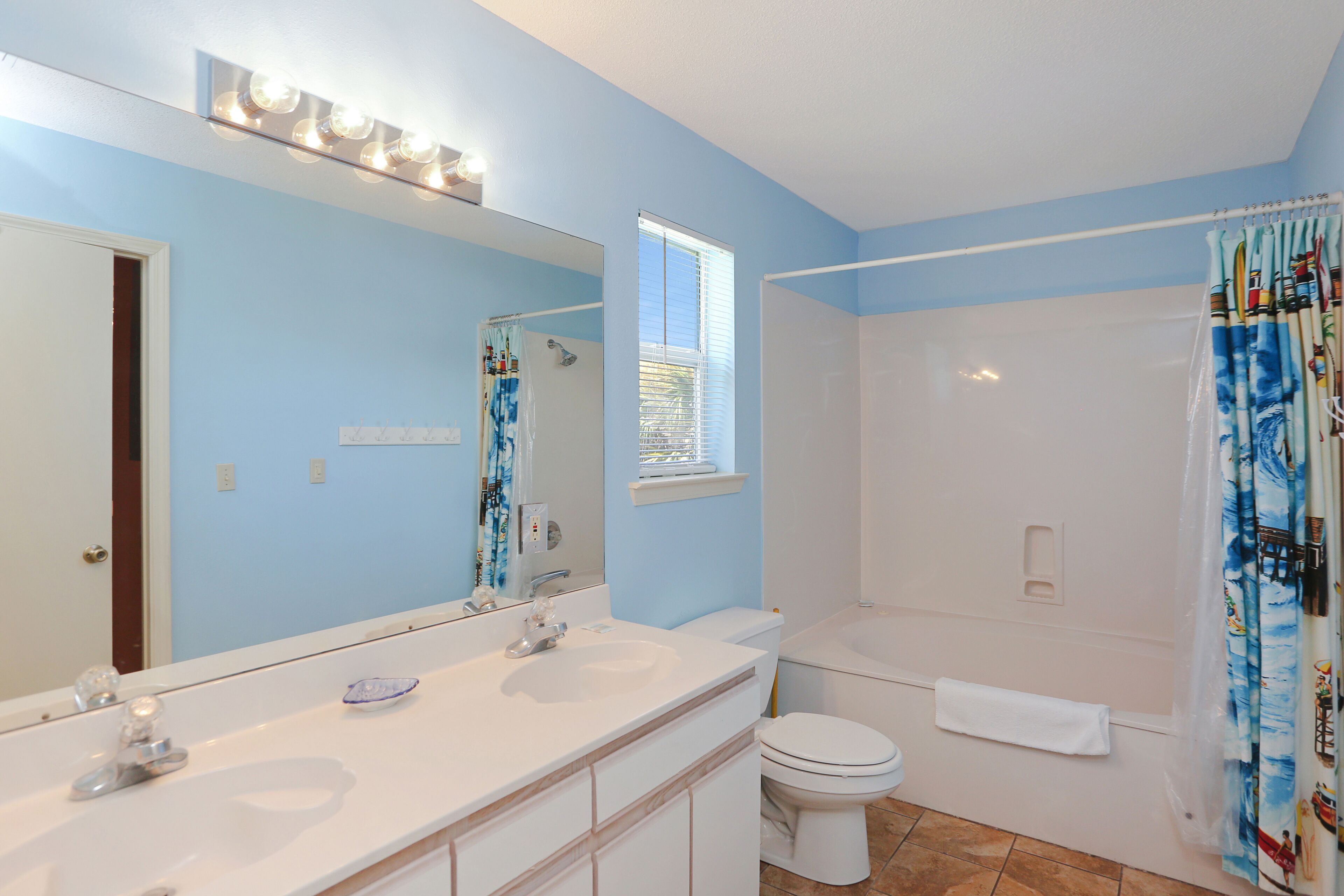 Une salle de bain avec deux lavabos, des toilettes, une baignoire et un rideau de douche.