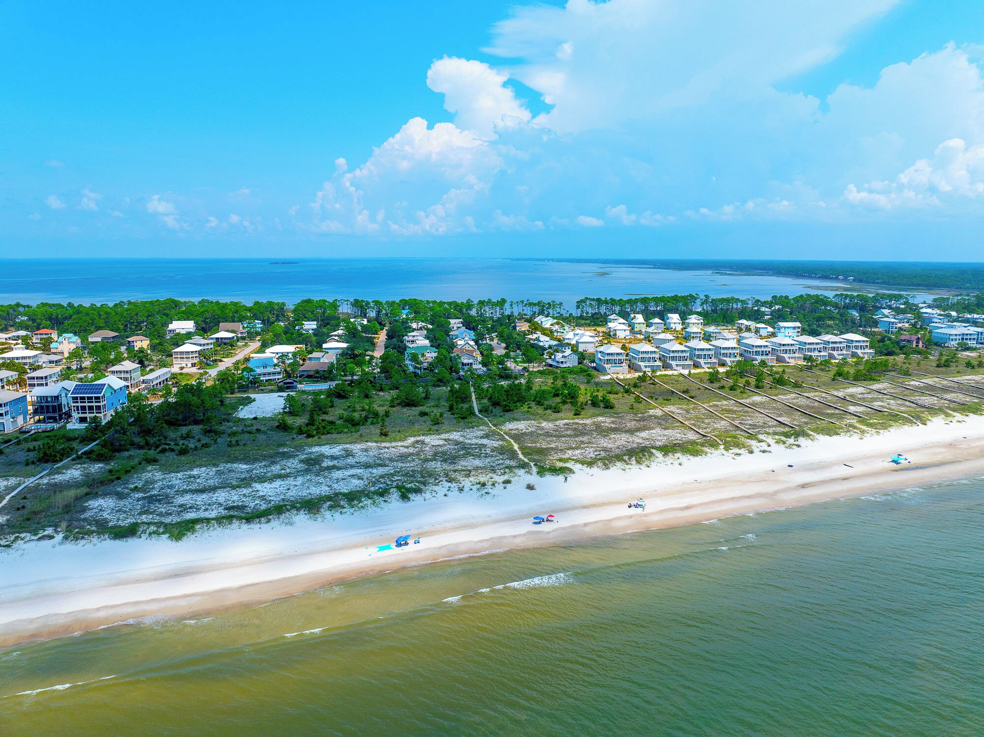 Un quartier résidentiel situé sur la côte, avec des propriétés donnant sur la plage, une plage de sable et une vue dégagée sur l’océan.