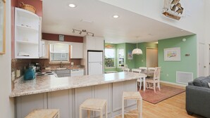 Une cuisine moderne avec des meubles blancs, un plan de travail en granit et un coin repas comprenant une table et des chaises.