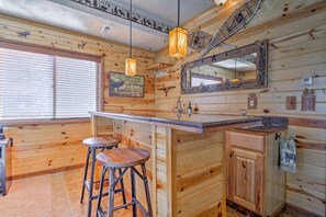 Cozy cabin-style interior with a bar area, large mirror, and framed picture.