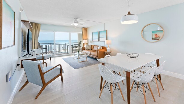A modern living room with a dining area, a sofa, and a view of the ocean. - Direct Oceanfront Condo with Heated Pool, BBQ Grills, Private Balcony & Beach Access! 🌴 (Satellite Beach)