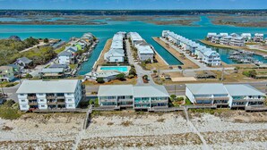 Un complejo turístico frente al mar con varias edificaciones, un puerto deportivo y una playa.