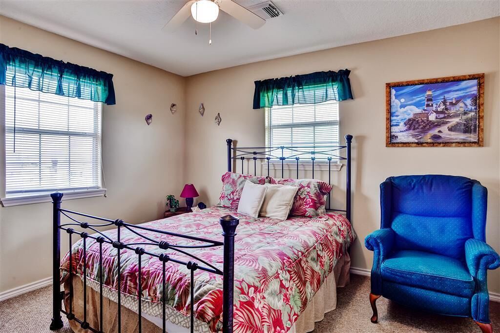 A bedroom with a bed, a chair, and a painting on the wall.