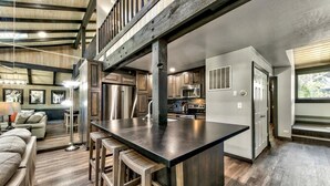 A spacious kitchen with a large island, wooden bar stools, and modern appliances.