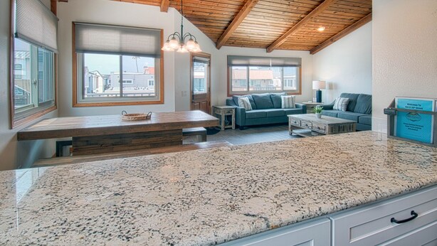 A spacious kitchen with granite countertops, a wooden ceiling, and a seating area with a sofa and a coffee table.