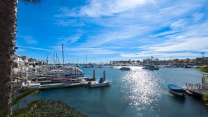 A marina with various boats docked, a clear blue sky, and a calm sea.