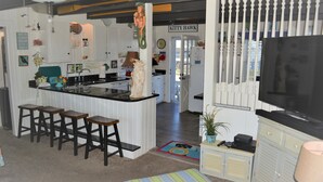Eine Küche mit Bar, weißen Schränken und einem Fernseher.