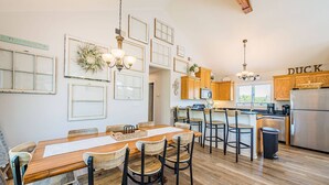 A spacious kitchen with wooden cabinets, a stainless steel refrigerator, and a dining area with a wooden table and chairs. - Captain's Perch - Duck, Northpoint, 400 Yds to Beach, Pool, Hot Tub, Events, Flex Stays (Duck)