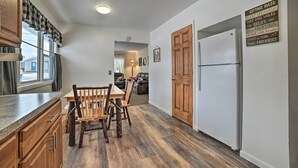 A kitchen with wooden cabinets, a dining table with chairs, a refrigerator, and a sign with cottage rules. - Cozy Houghton Lake Heights Cottage w/ Private Yard (Houghton Lake Heights)