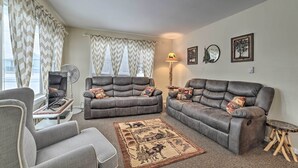 A living room with two grey sofas, a grey armchair, a small table, a floor lamp, and a decorative rug. - Cozy Houghton Lake Heights Cottage w/ Private Yard (Houghton Lake Heights)